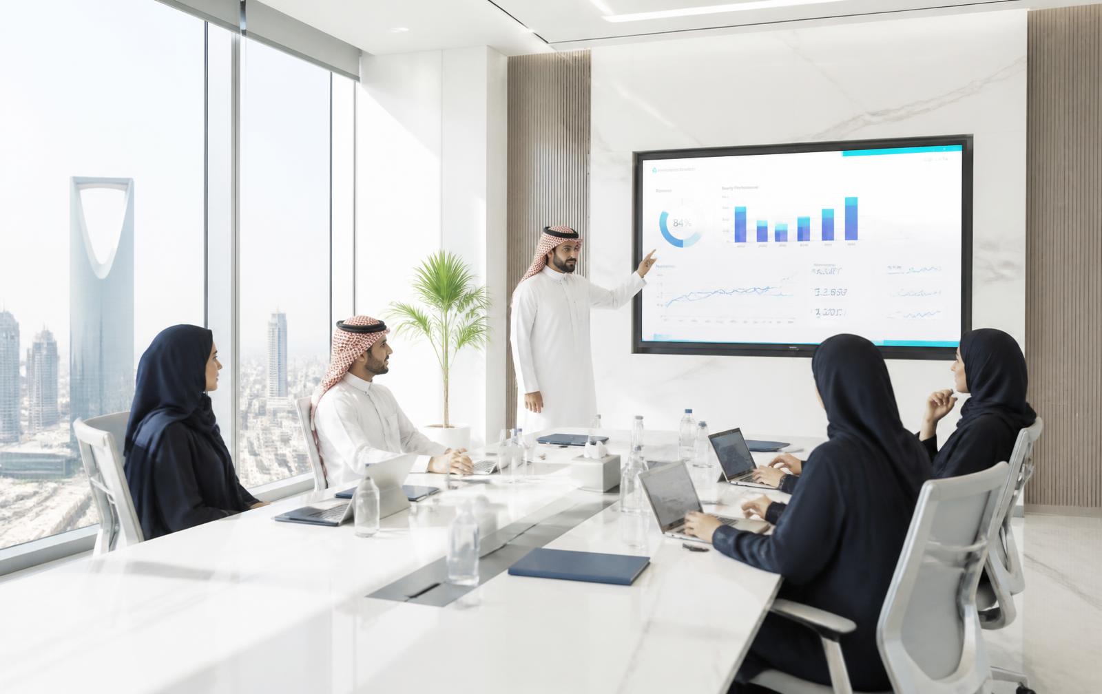 Saudi executives reviewing AI performance metrics in a bright Riyadh boardroom